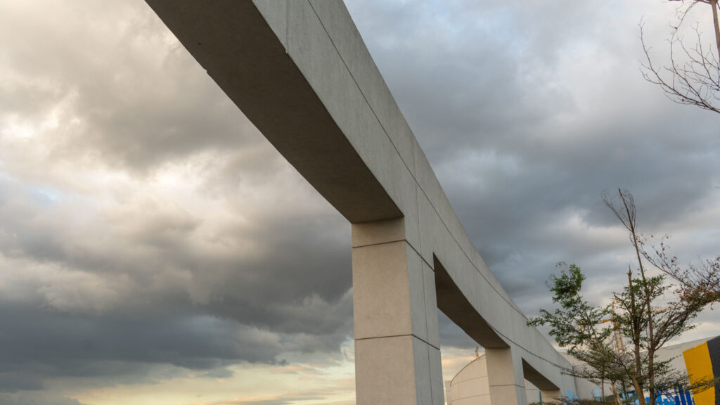 Close-up view of a modern white arch bridge with steel suspension cables against a clear sky.